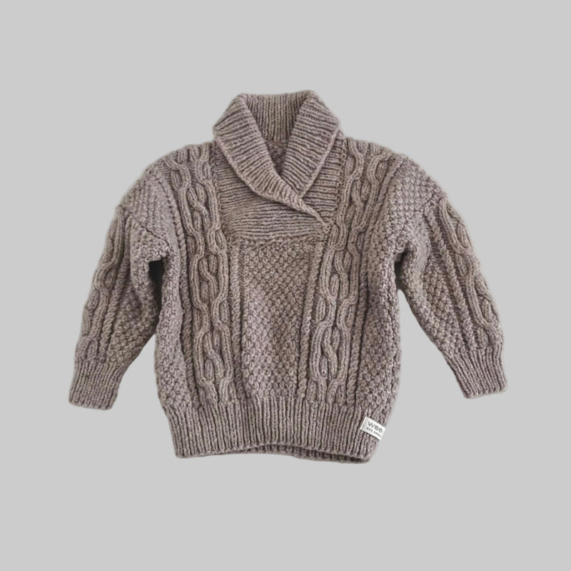 Knitted sweater with cable pattern on a grey background