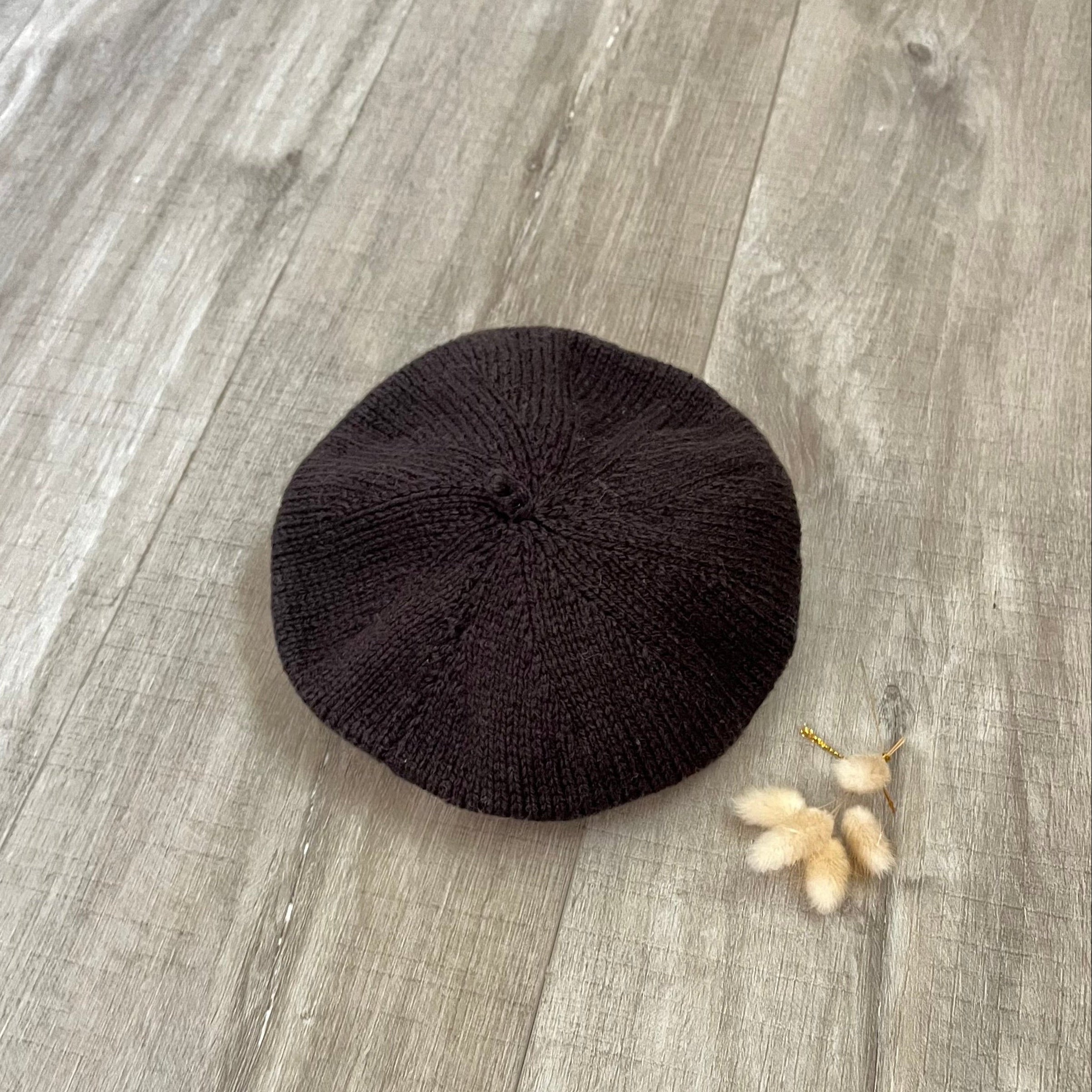 chocolate beret on a wooden surface with dried flowers.