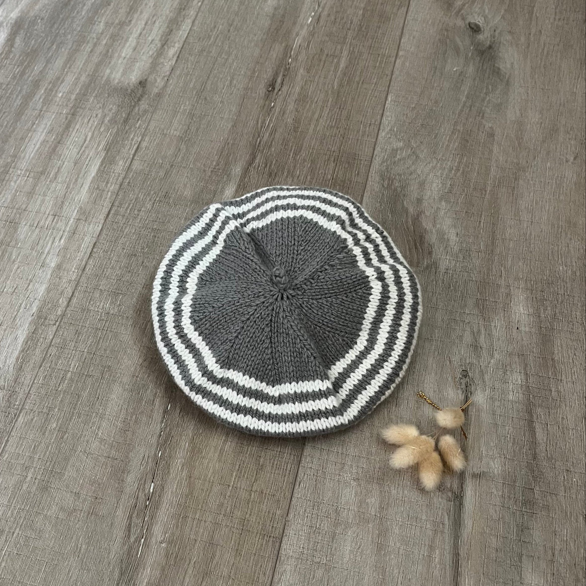 Knitted mushroom and natural stripe beret on a wooden floor