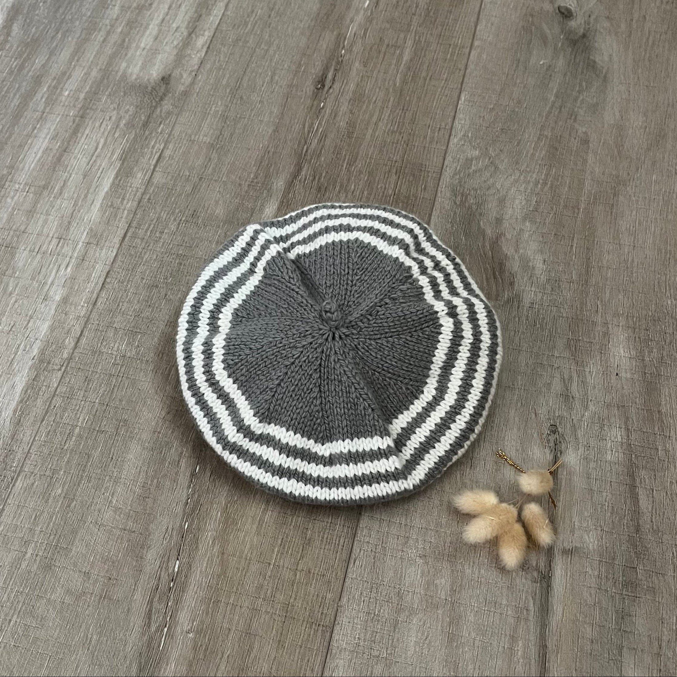 Knitted mushroom and natural stripe beret on a wooden floor