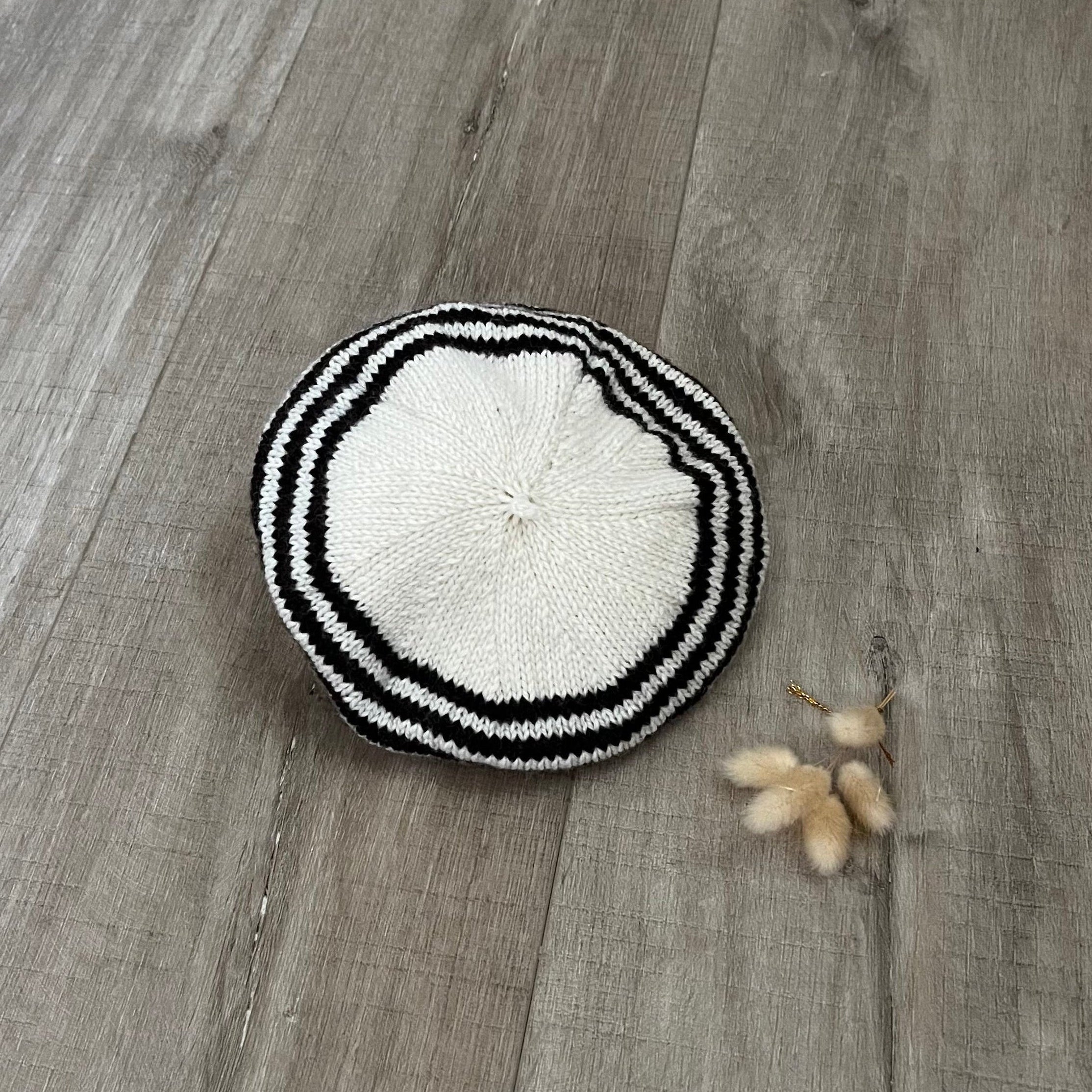 Chocolate and white knitted beret on a wooden surface