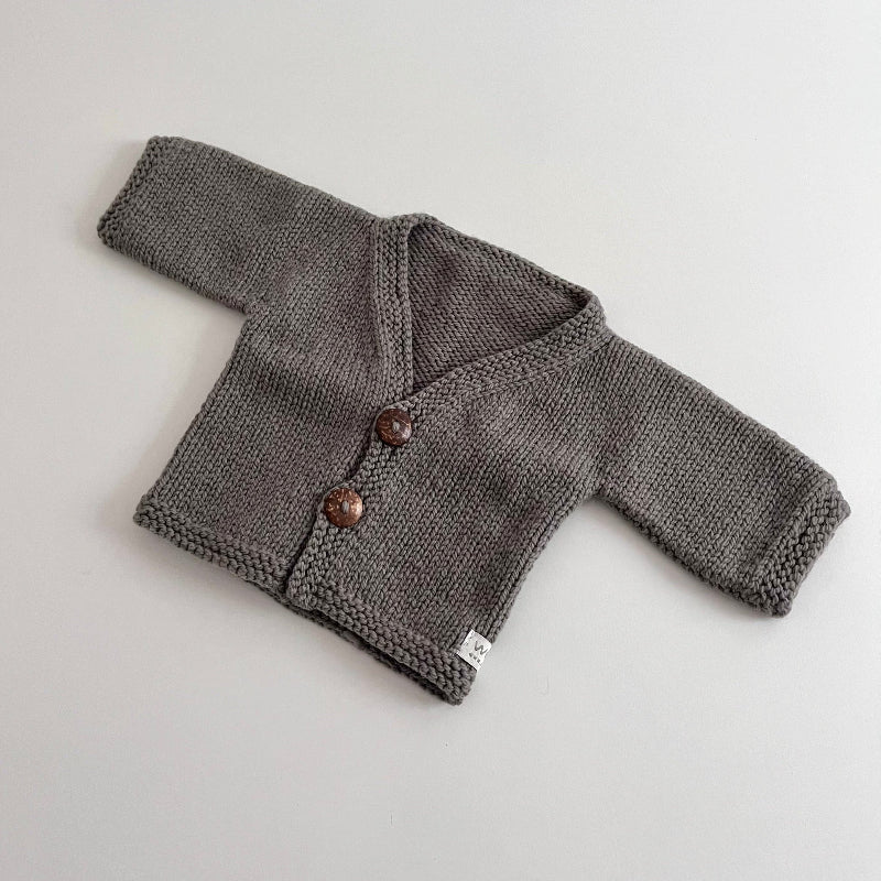 Knitted mushroom baby cardigan with buttons on a light grey background