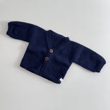 Navy knitted baby cardigan on a light grey background