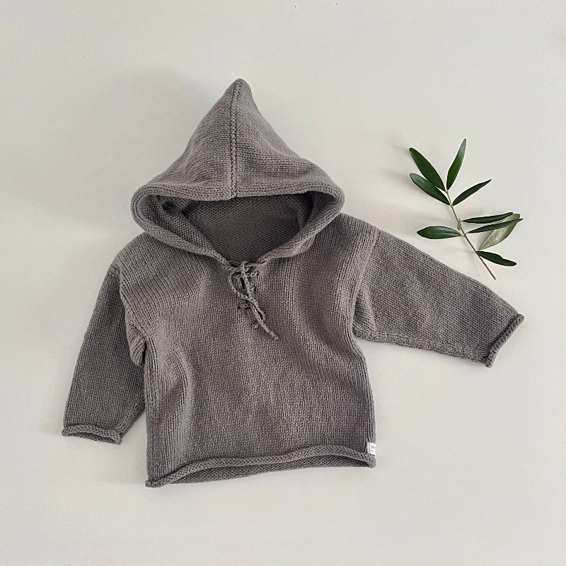 Mushroom children's hoodie on a white surface with a plant in the background