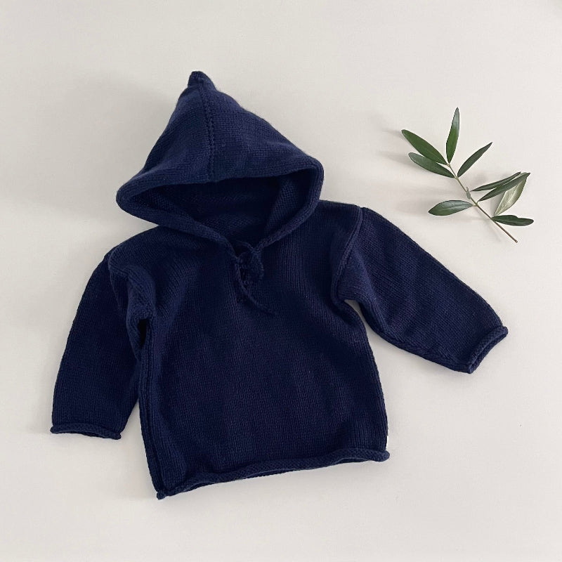 Navy blue baby hoodie on a white surface with a plant in the background