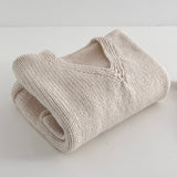 Folded natural knitted jumper on a white surface