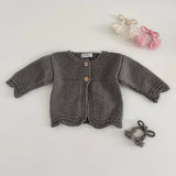 Mushroom coloured knitted baby cardigan on a light grey background