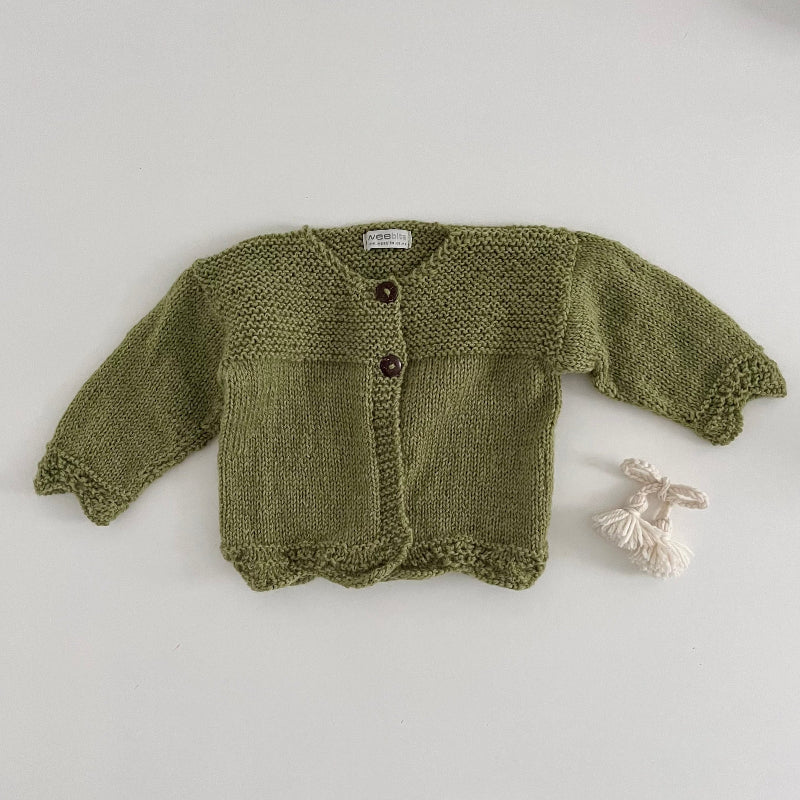 Pistachio coloured knitted baby cardigan on a light grey background