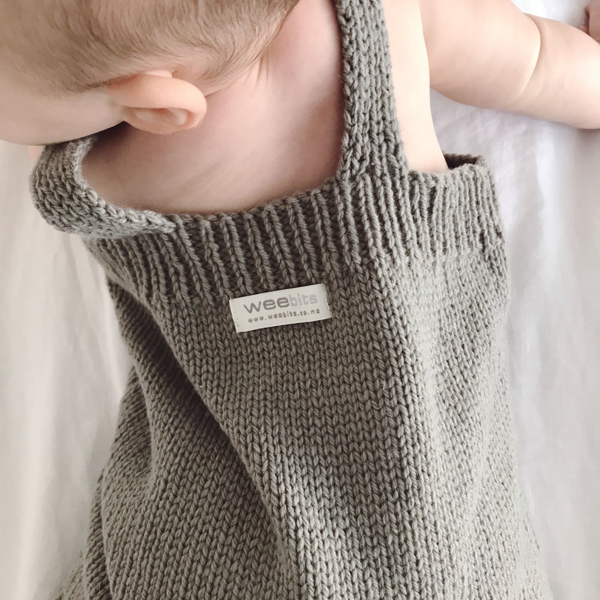 Closeup of a baby wearing a weebits merino knitted romper.