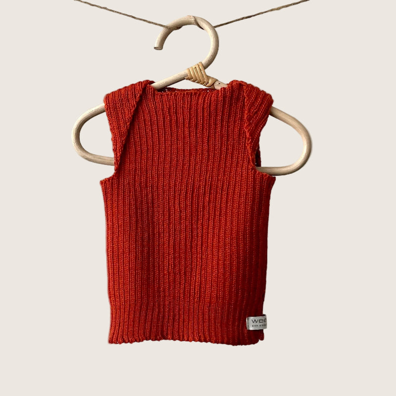 Burnt orange ribbed baby singlet hanging on a wooden hanger against a plain background
