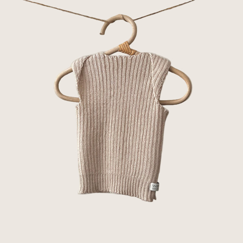 Sand ribbed baby singlet hanging on a wooden hanger against a plain background