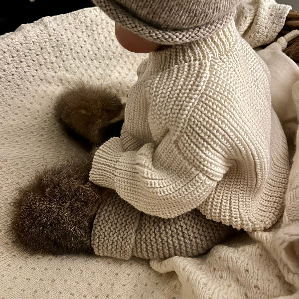 baby sitting up wearing possum booties