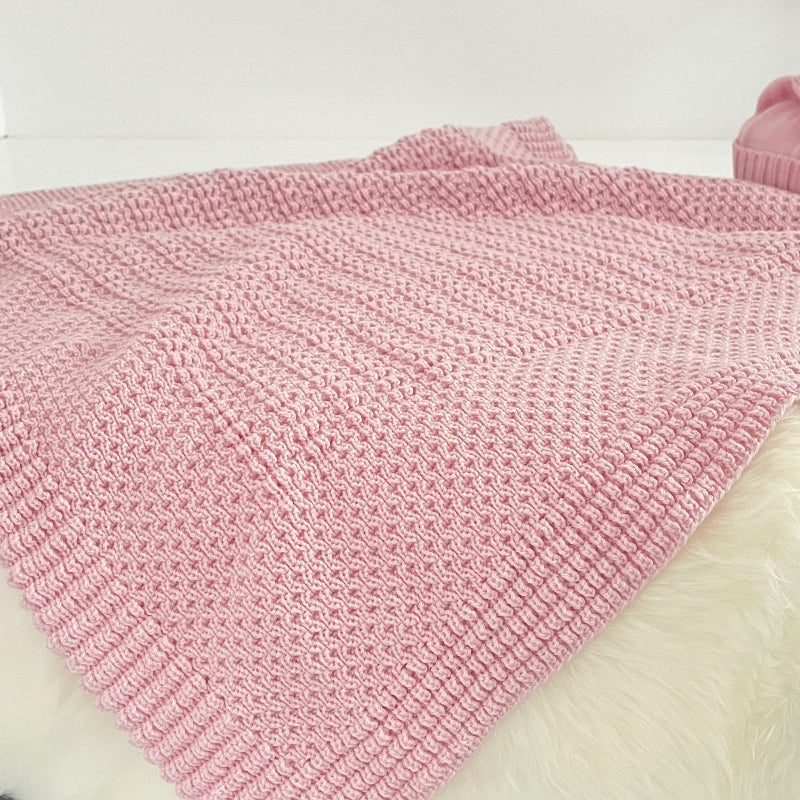 Blossom pink merino bassinet blanket on sheepskin rug