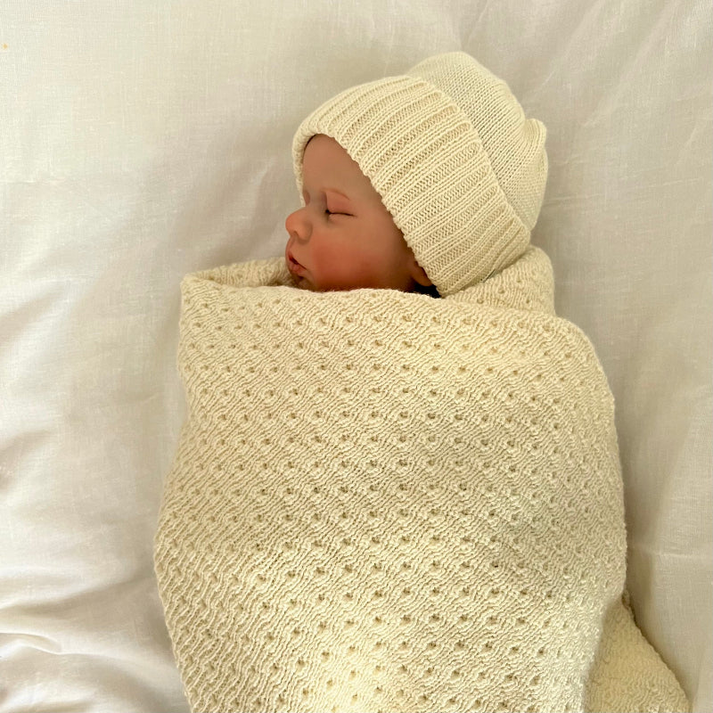 Baby sleeping in butter milk merino baby wrap and beanie