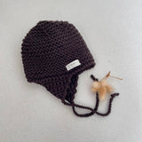 Knitted chunky knit baby hat chocolate colour on a light grey background