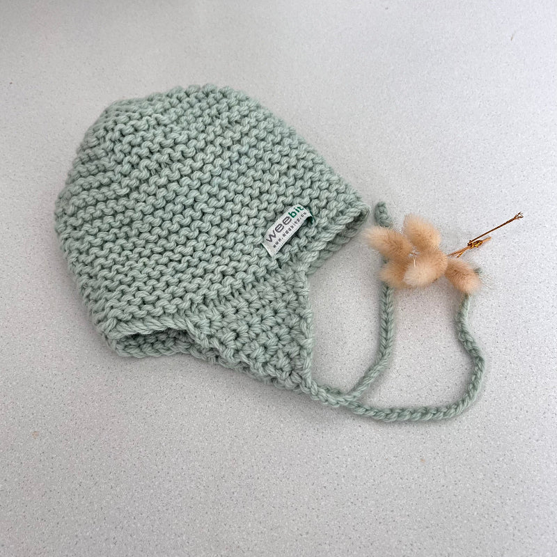 Knitted chunky knit baby hat mint colour on a light grey background