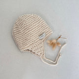Knitted chunky knit baby hat natural colour on a light grey background