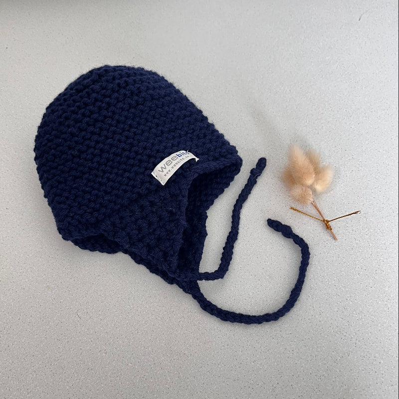 Knitted chunky knit baby hat navy colour on a light grey background