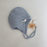 Knitted chunky knit baby hat blue colour on a light grey background