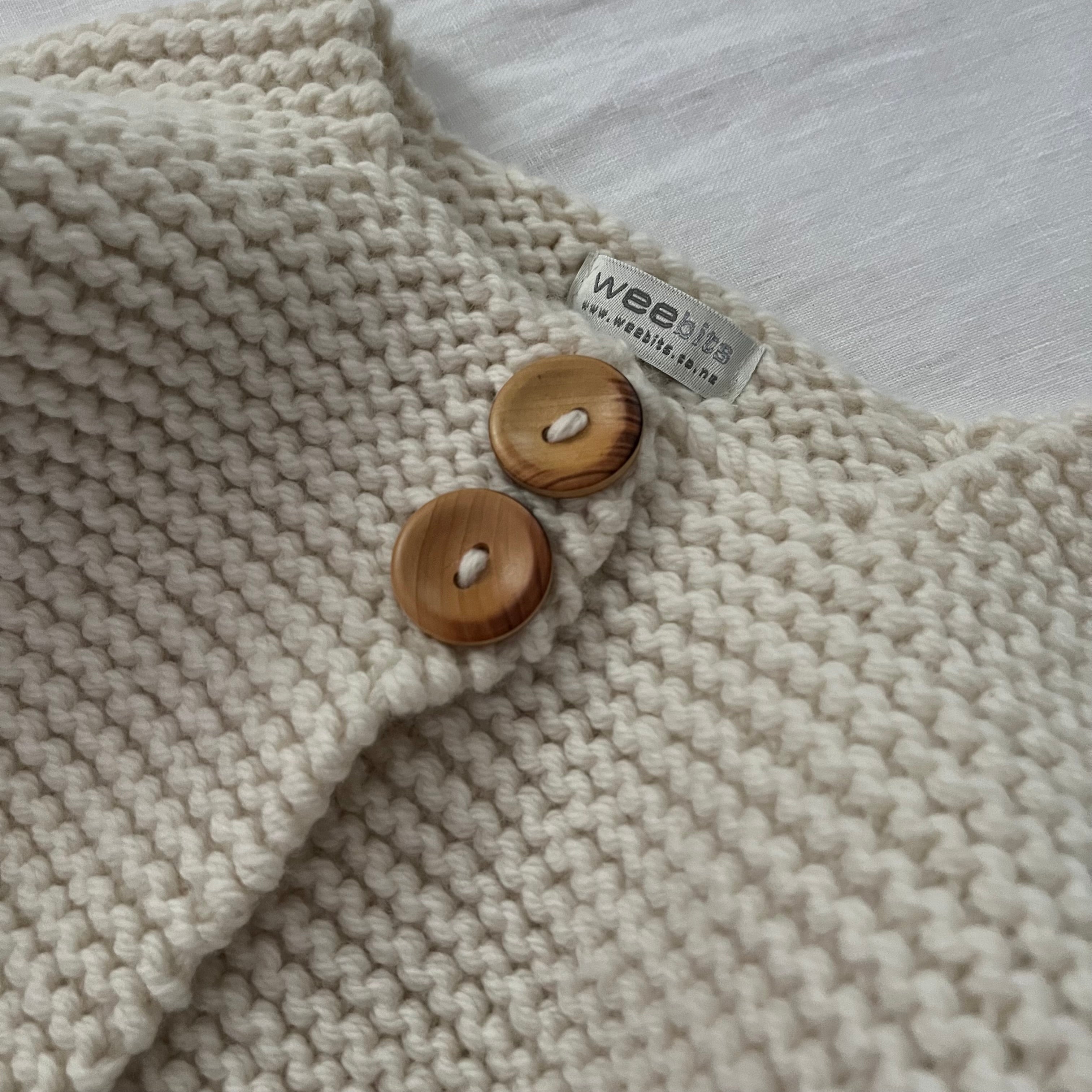close up of button detail of chunky knit baby jacket