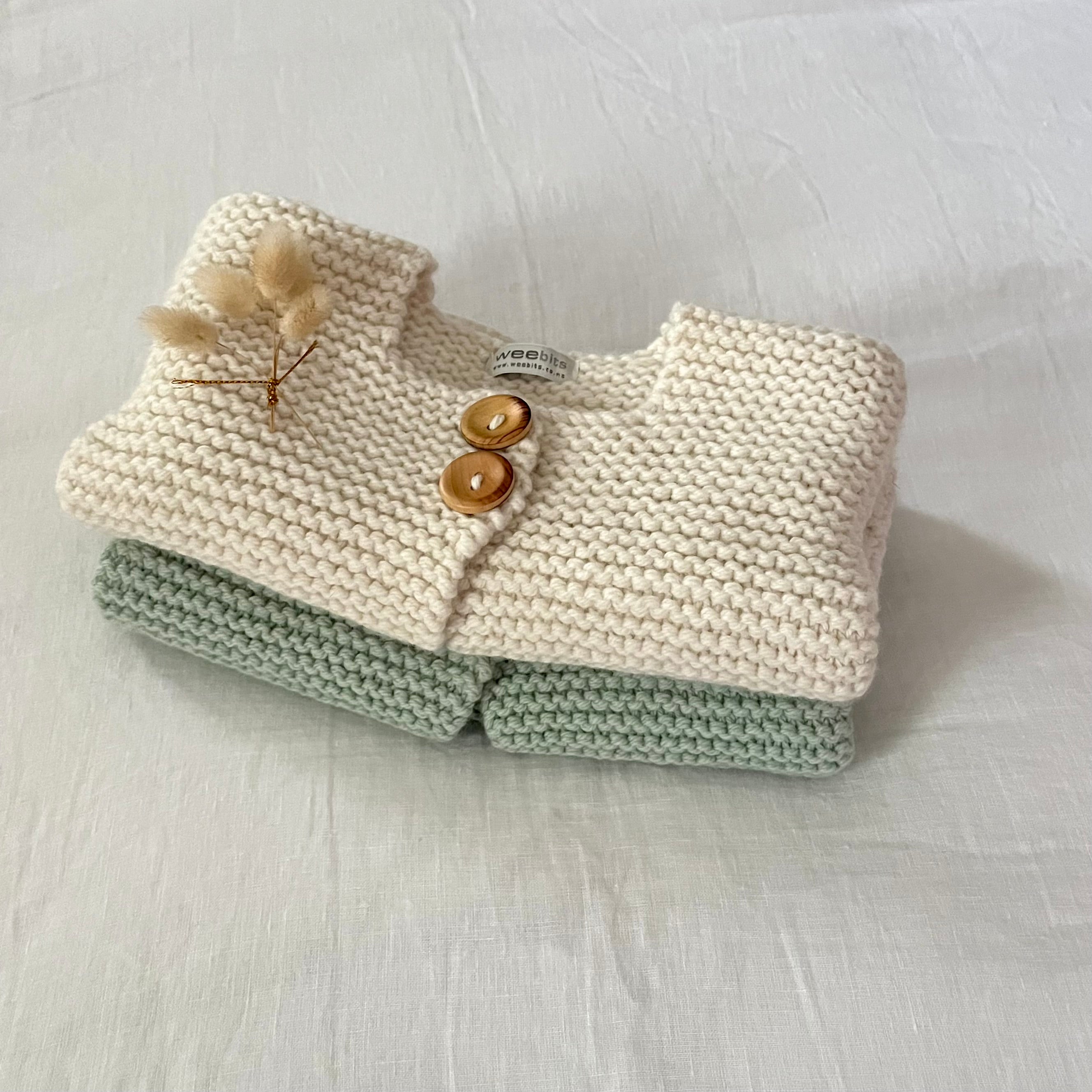 Mint and natural chunky knit jackets folded on a natural background