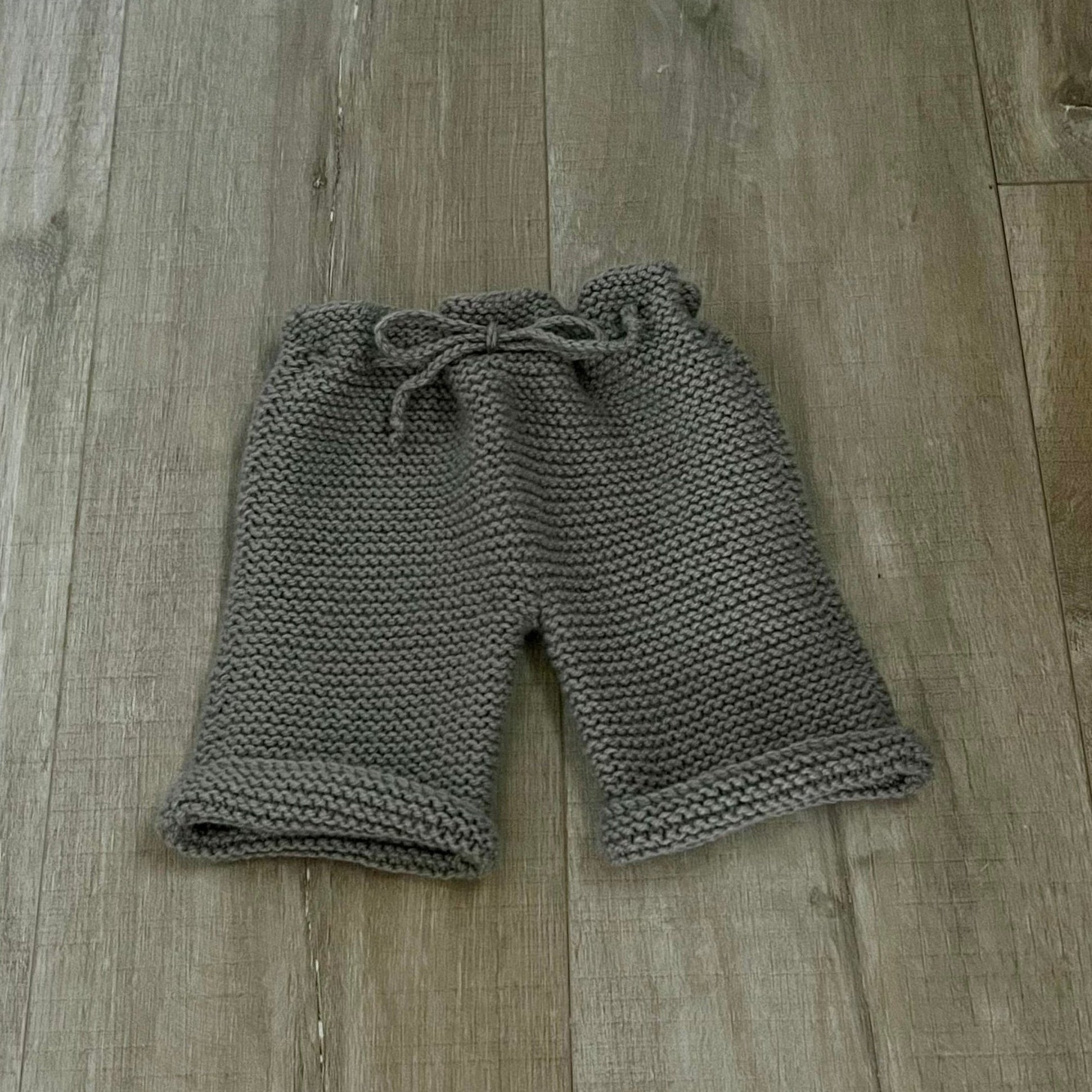 Knitted baby pants on a wooden floor