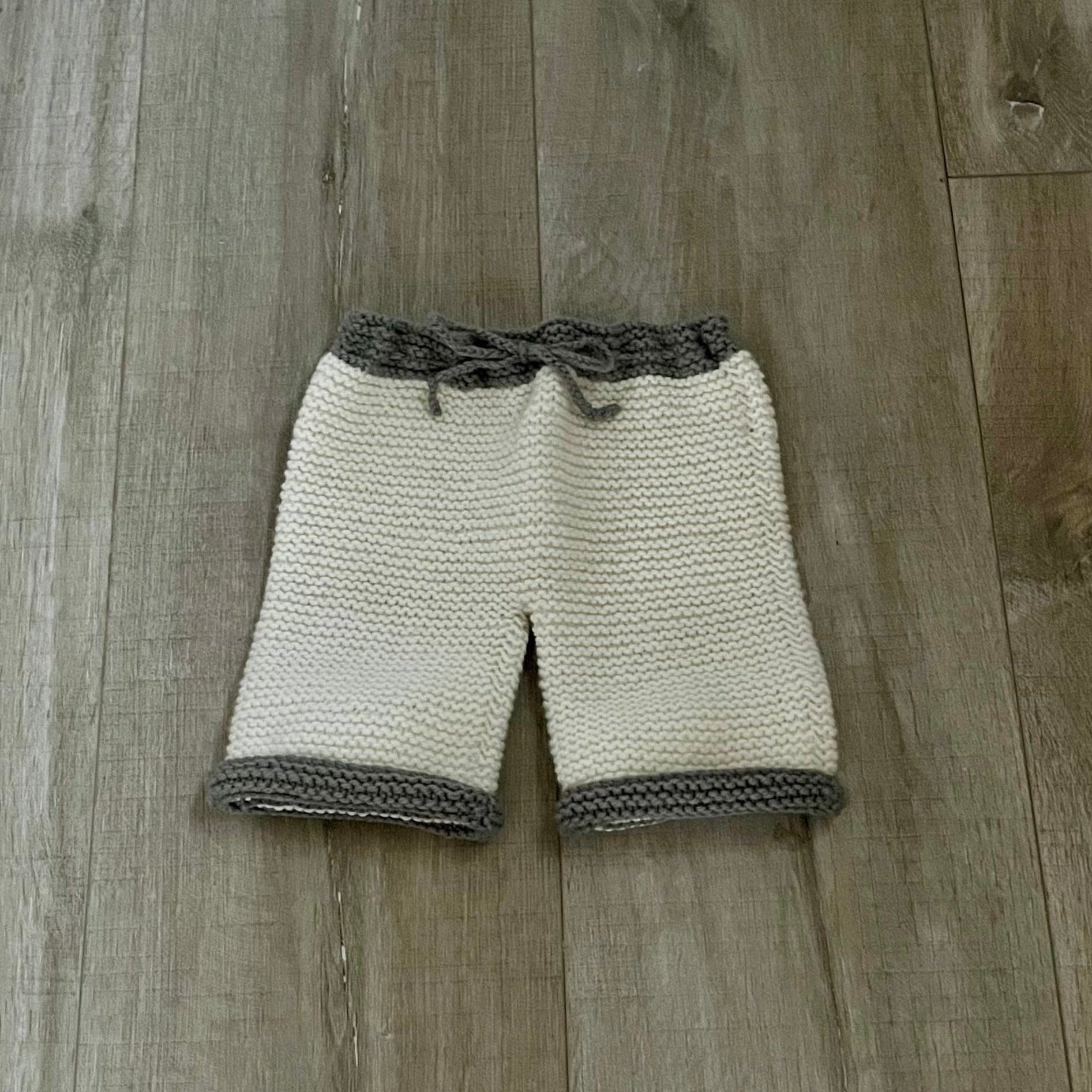 Knitted pants with brown trim on a wooden floor