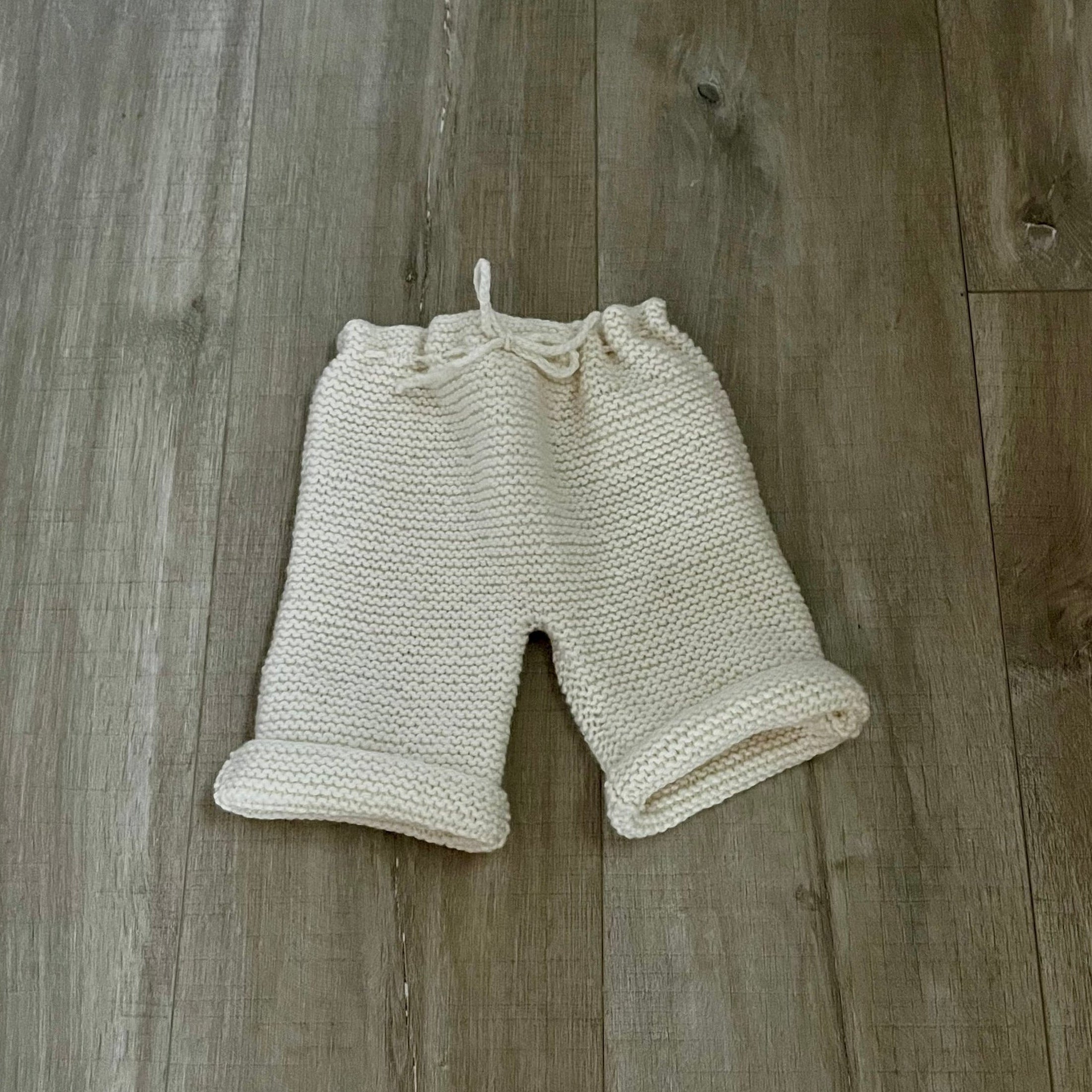 Knitted baby pants on a wooden floor