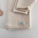 Knitted baby jumper with a visible brand label on a light background