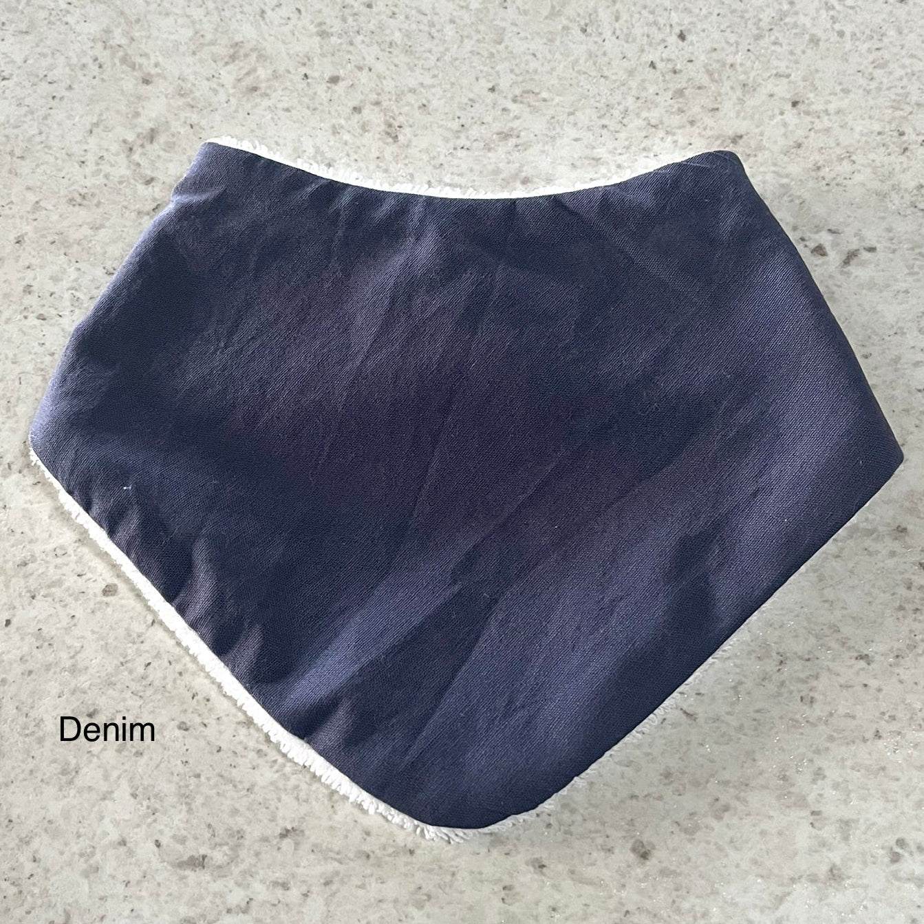Denim colored dribble bib on a textured gray surface