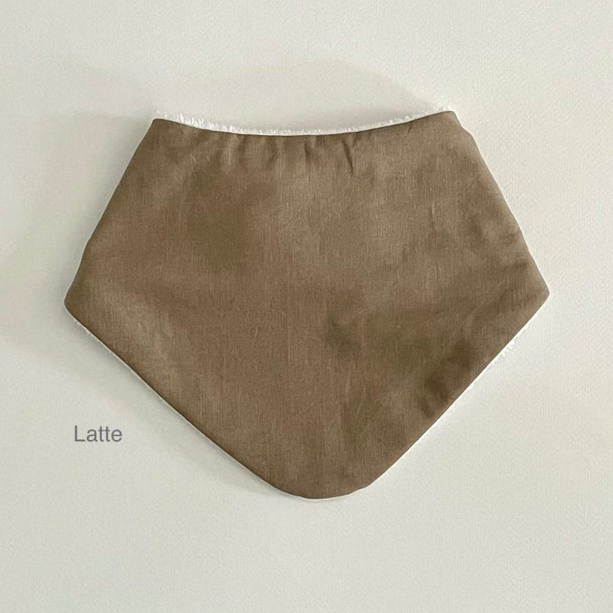 A fabric bandana bib in a matte taupe-brown color, labeled 'Latte' on the bottom left, displayed against a plain off-white background.