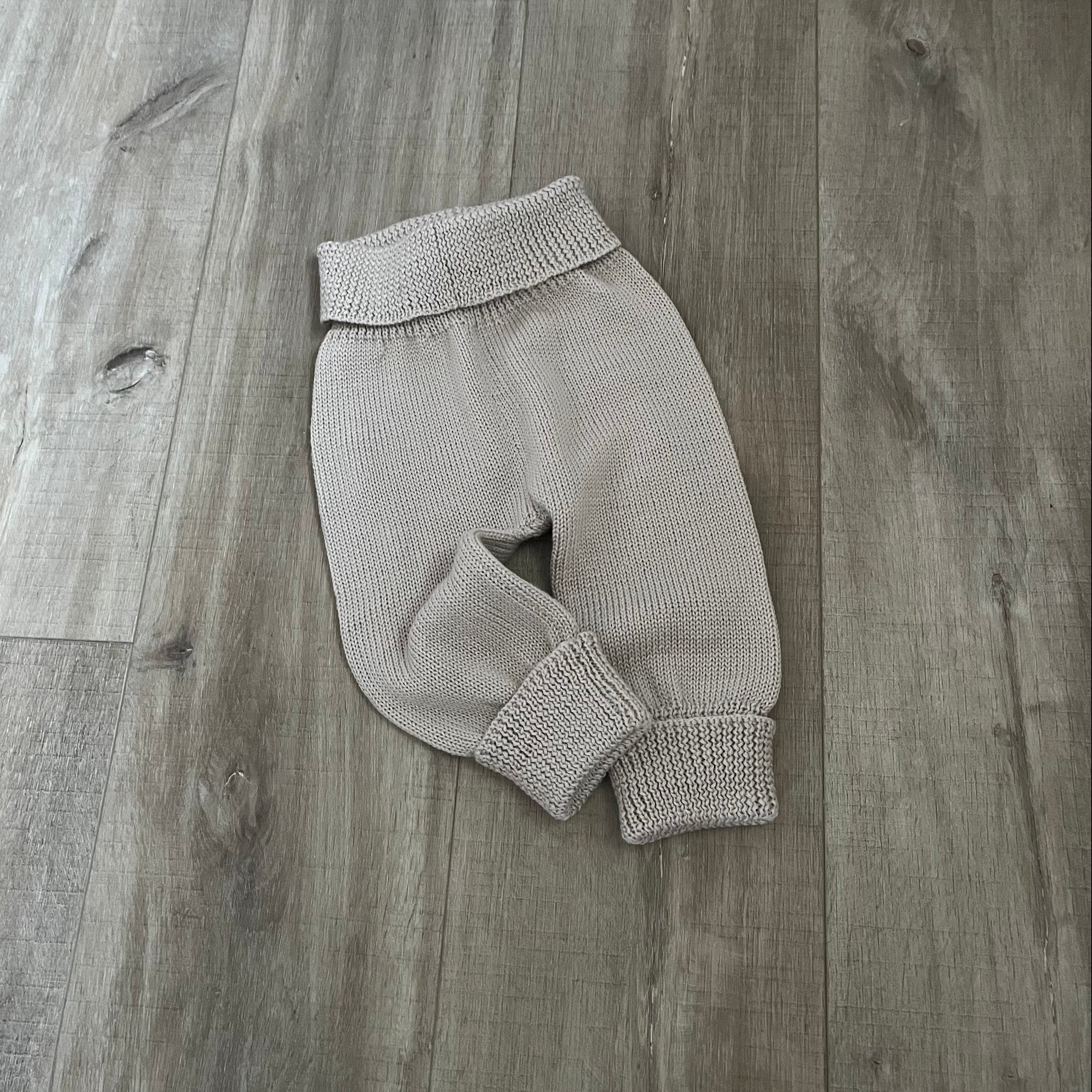 Baby knitted jodhpurs on wooden surface