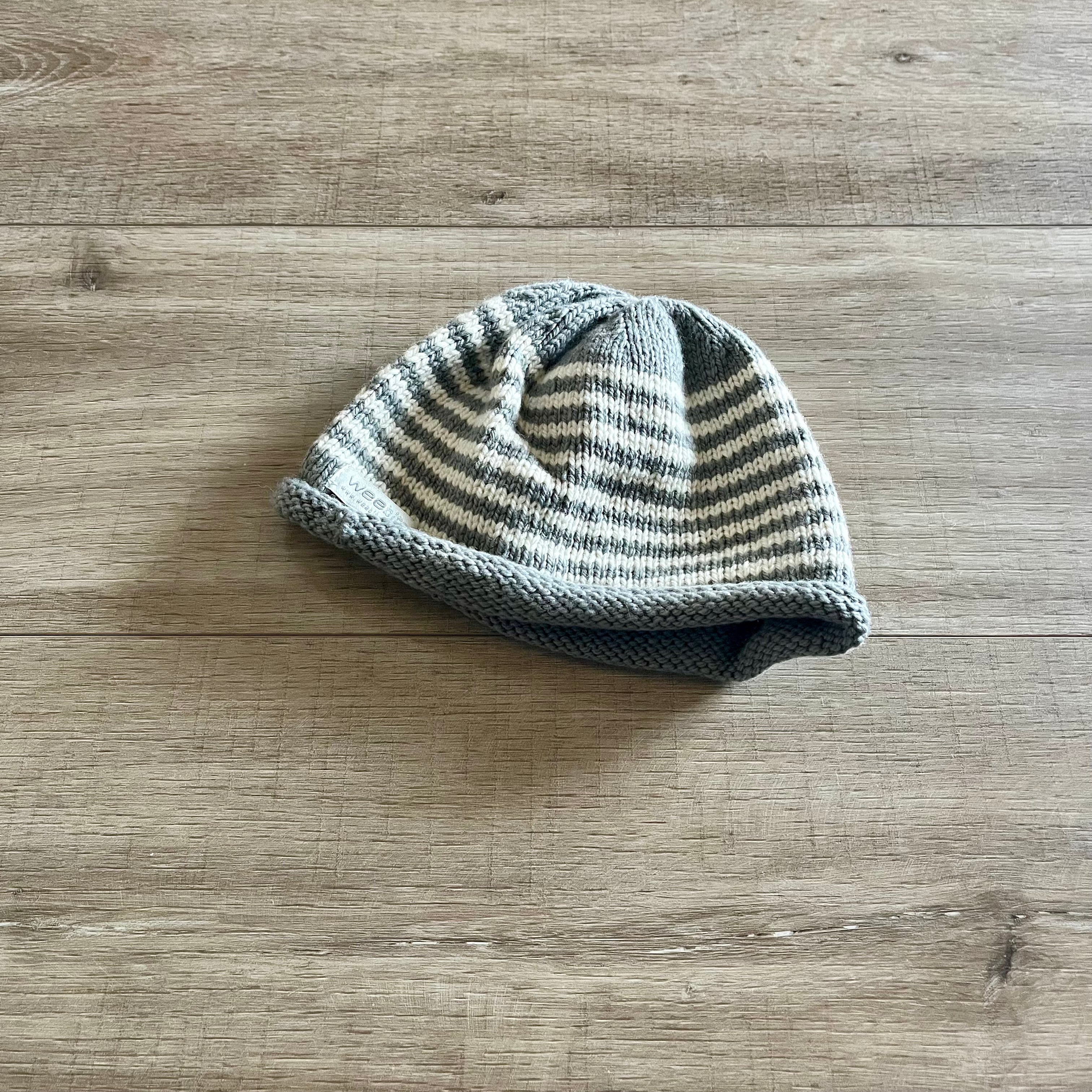 Knitted baby hat with striped pattern on a wooden surface