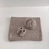 Knitted Oatmeal baby travel rug beanie and bootie set on white shelf