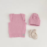 Baby pink vest, beanie, and socks on a light background
