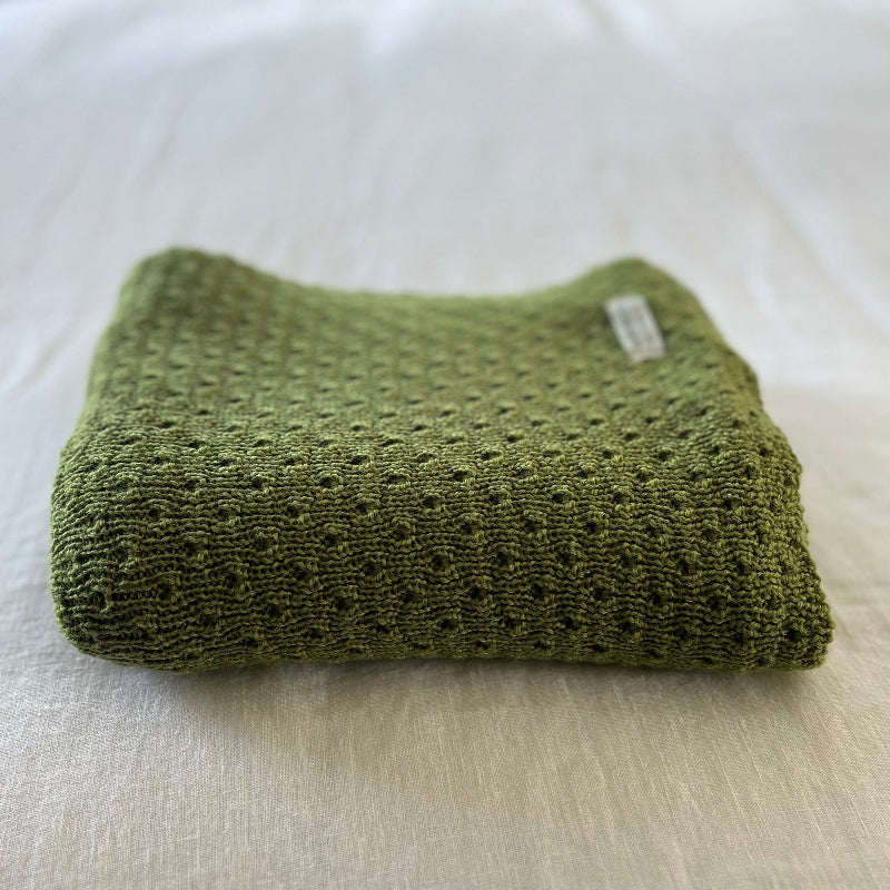 Moss merino baby wrap on cotton sheet