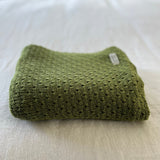 Moss merino baby wrap on cotton sheet