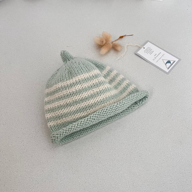 Mint and natural striped knit baby hat with a tag on a light grey background
