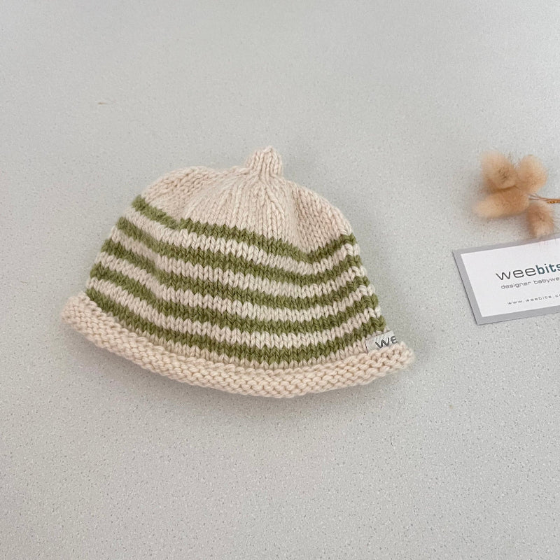 Natural and pistachio striped knit baby hat with a tag on a light grey background