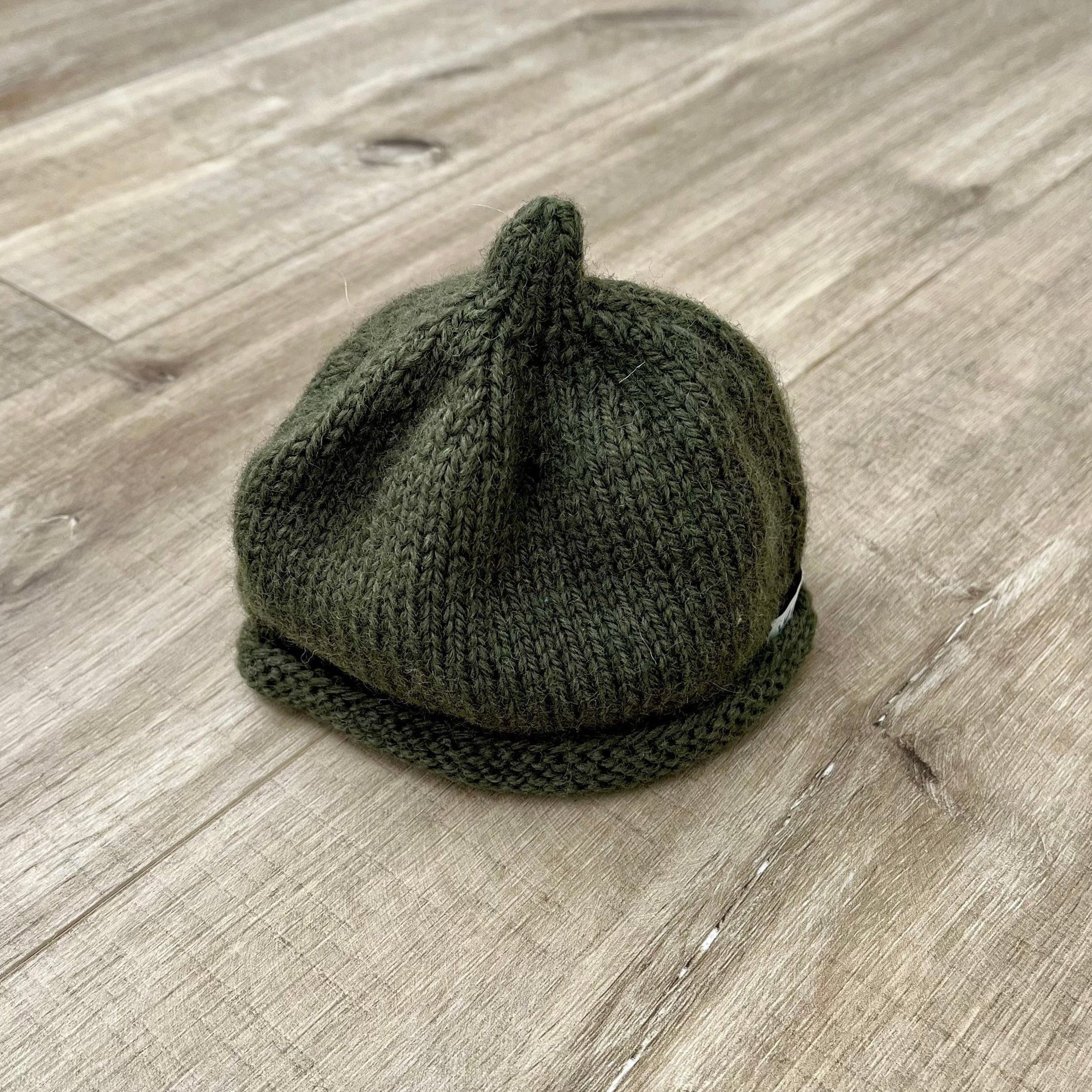 Baby-pixie-point-beanie-forest-green-colour-on-wooden-surface