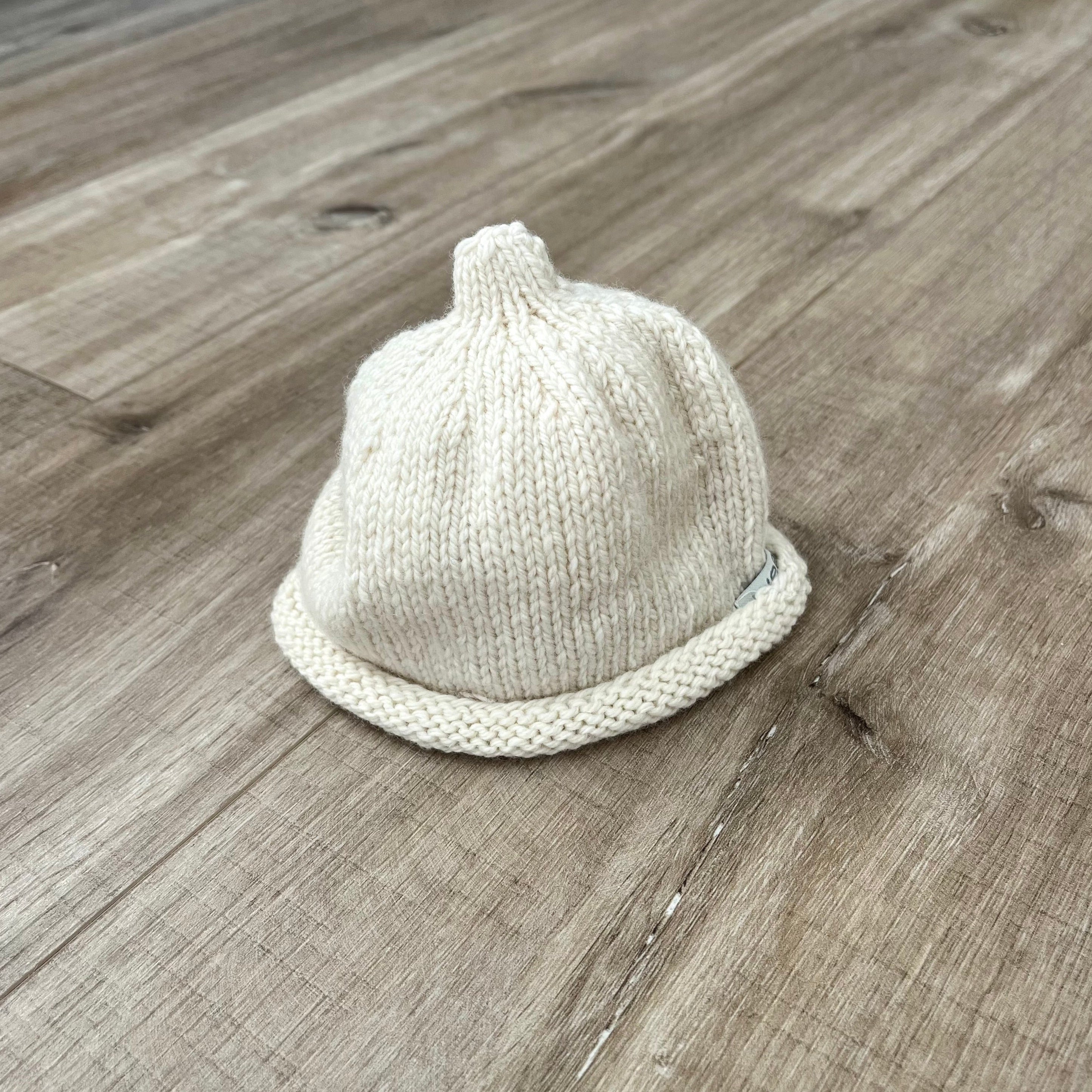 Baby-pixie-point-beanie--natural-colour-on-wooden-surface