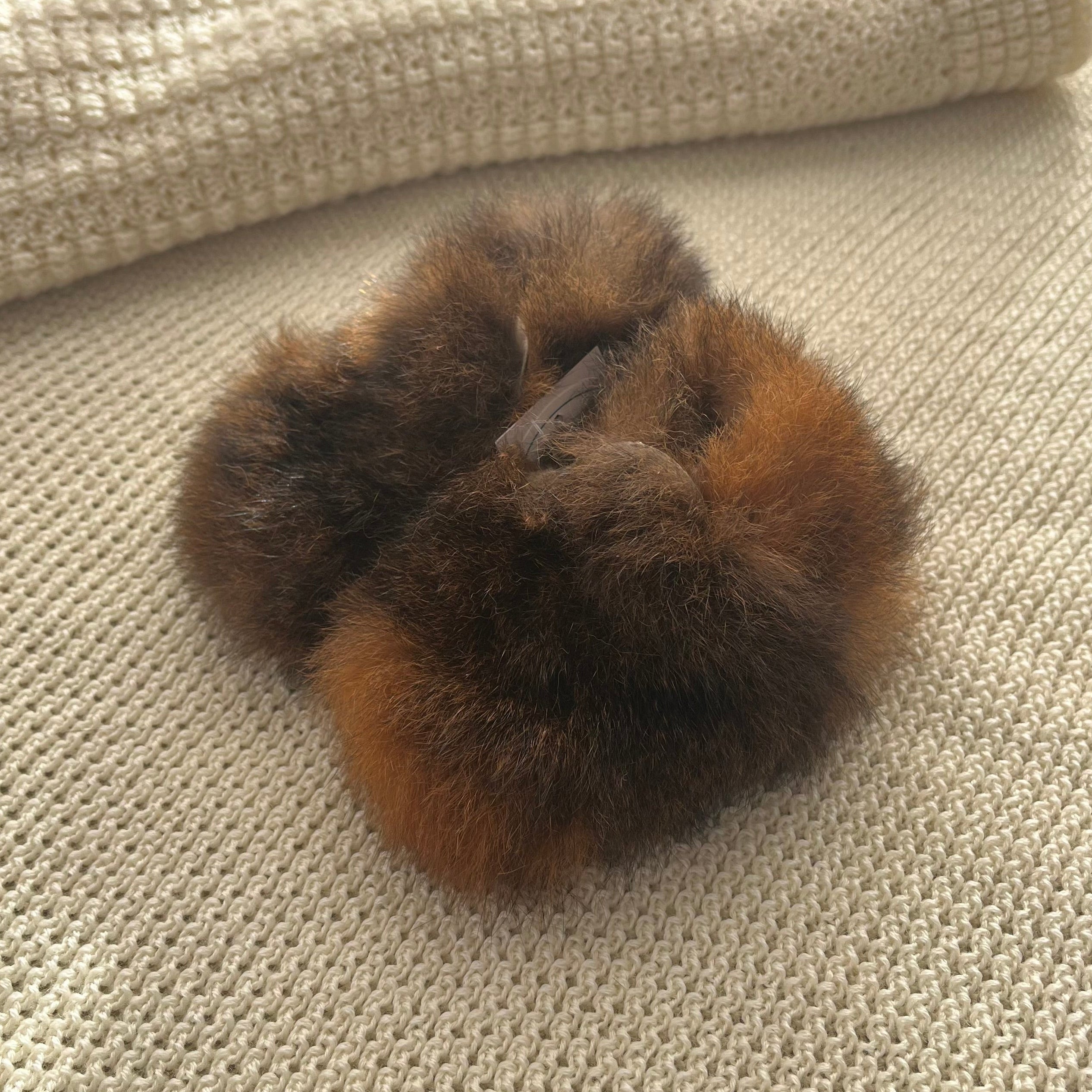 Brown fur possum booties on a beige textured surface