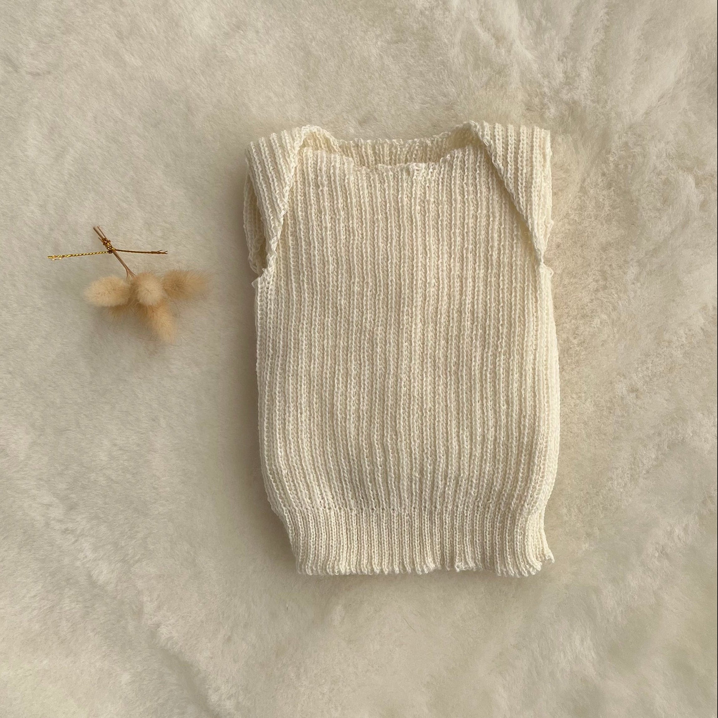 Cream premature baby vest on sheepskin rug