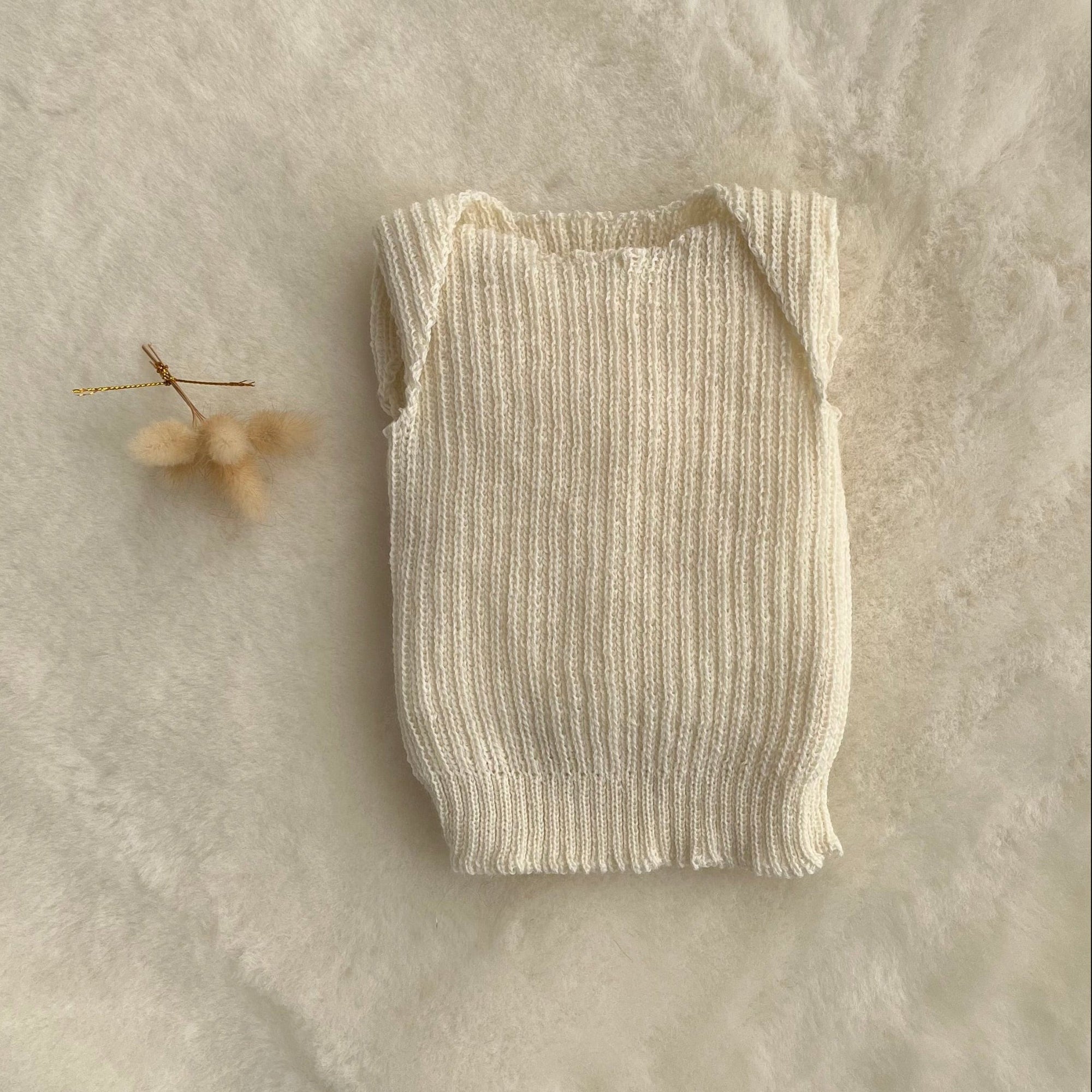 Cream premature baby vest on sheepskin rug