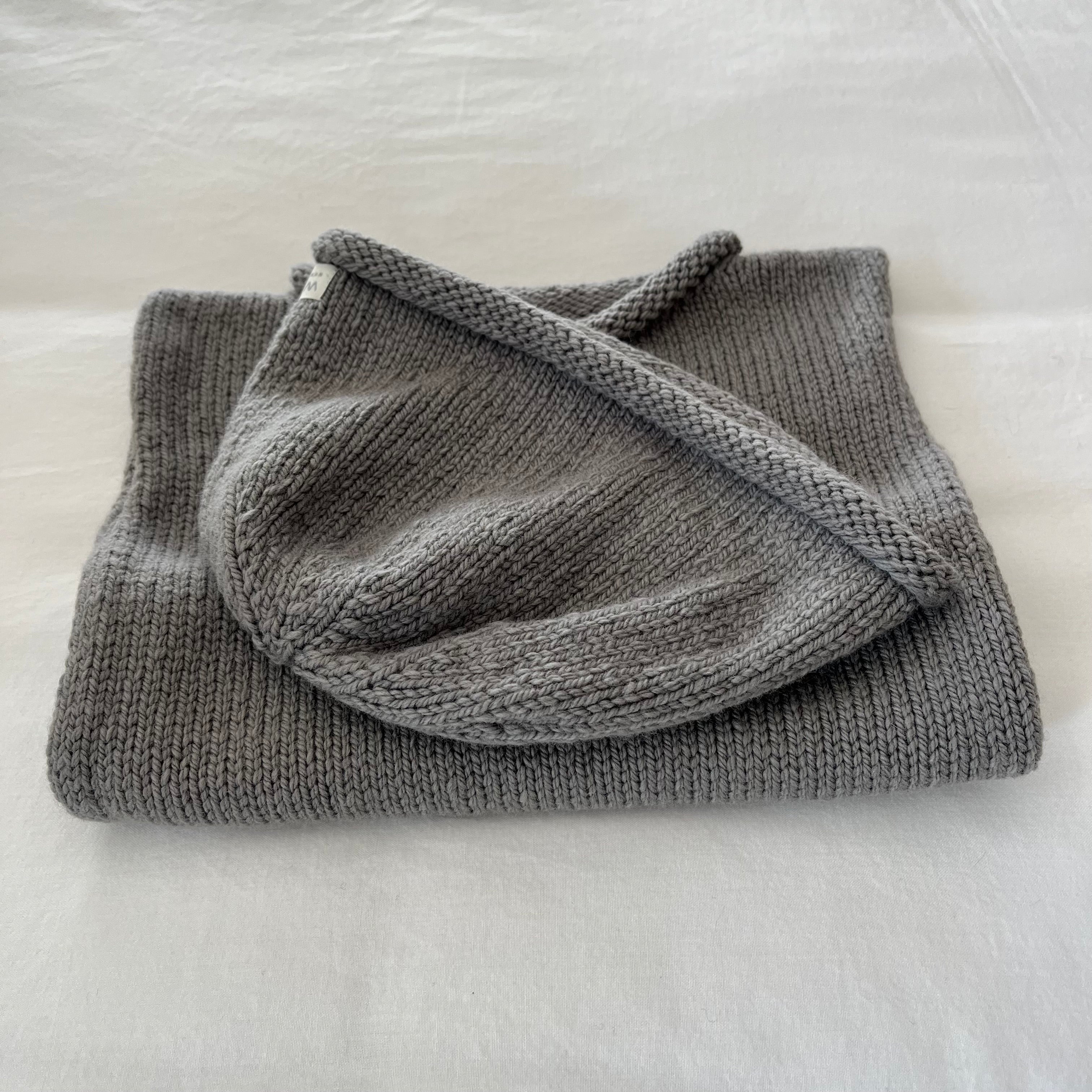 Folded mushroom knitted vest and beanie on a light gray surface