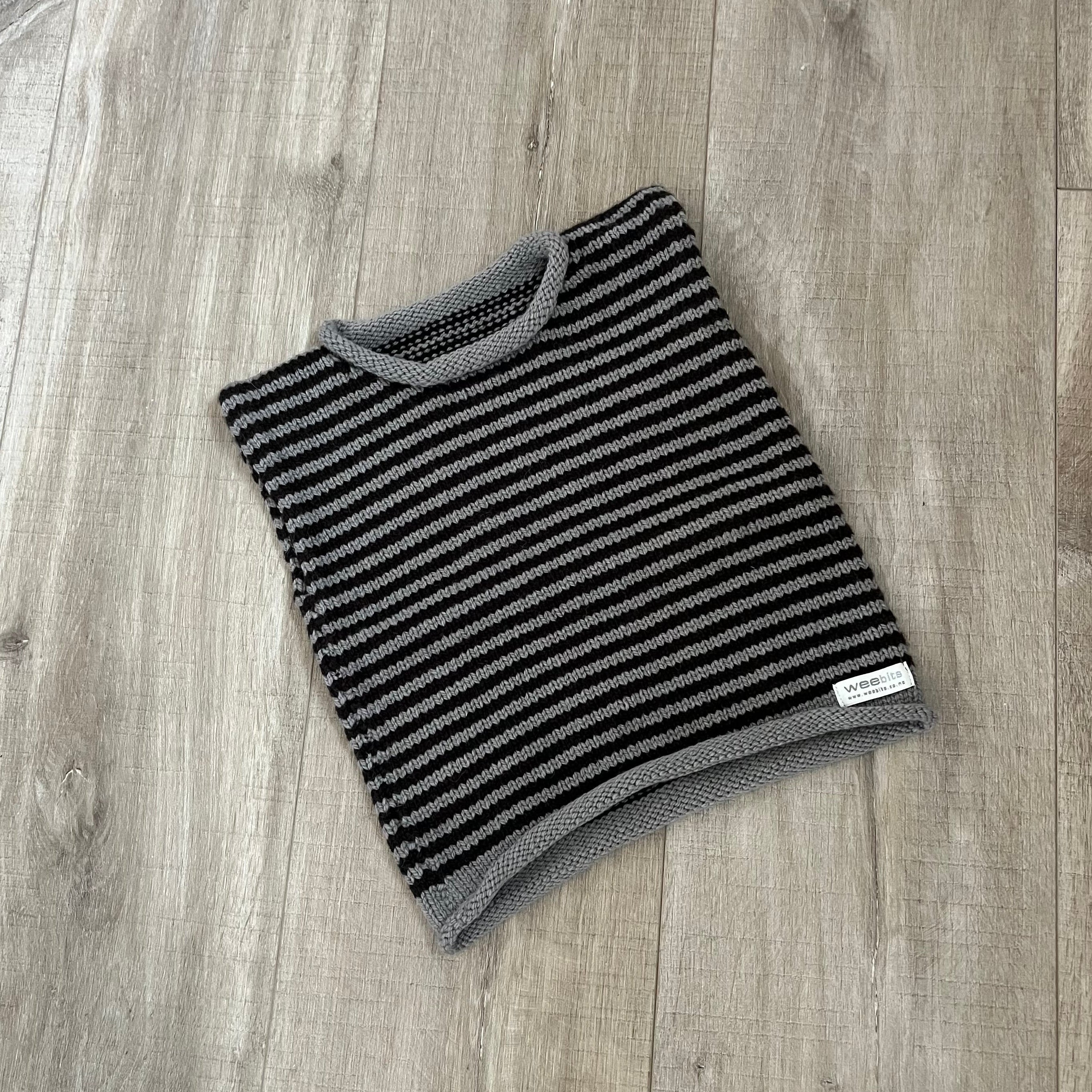 A mushroom stripe knit vest placed on a light brown wood surface.