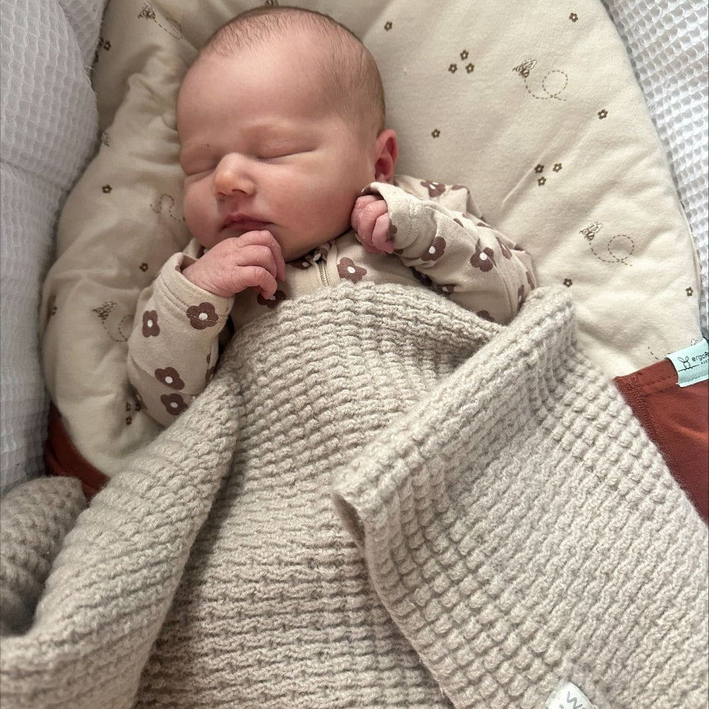 Sleeping baby wrapped in pram blanket