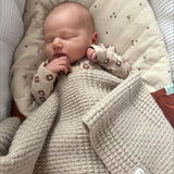 Sleeping baby wrapped in pram blanket