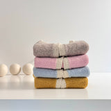 Stack of Chloe cardigans on white bench