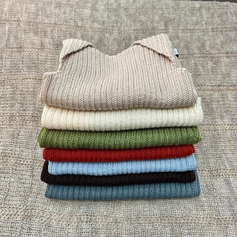 Stack of coloured merino baby singlets